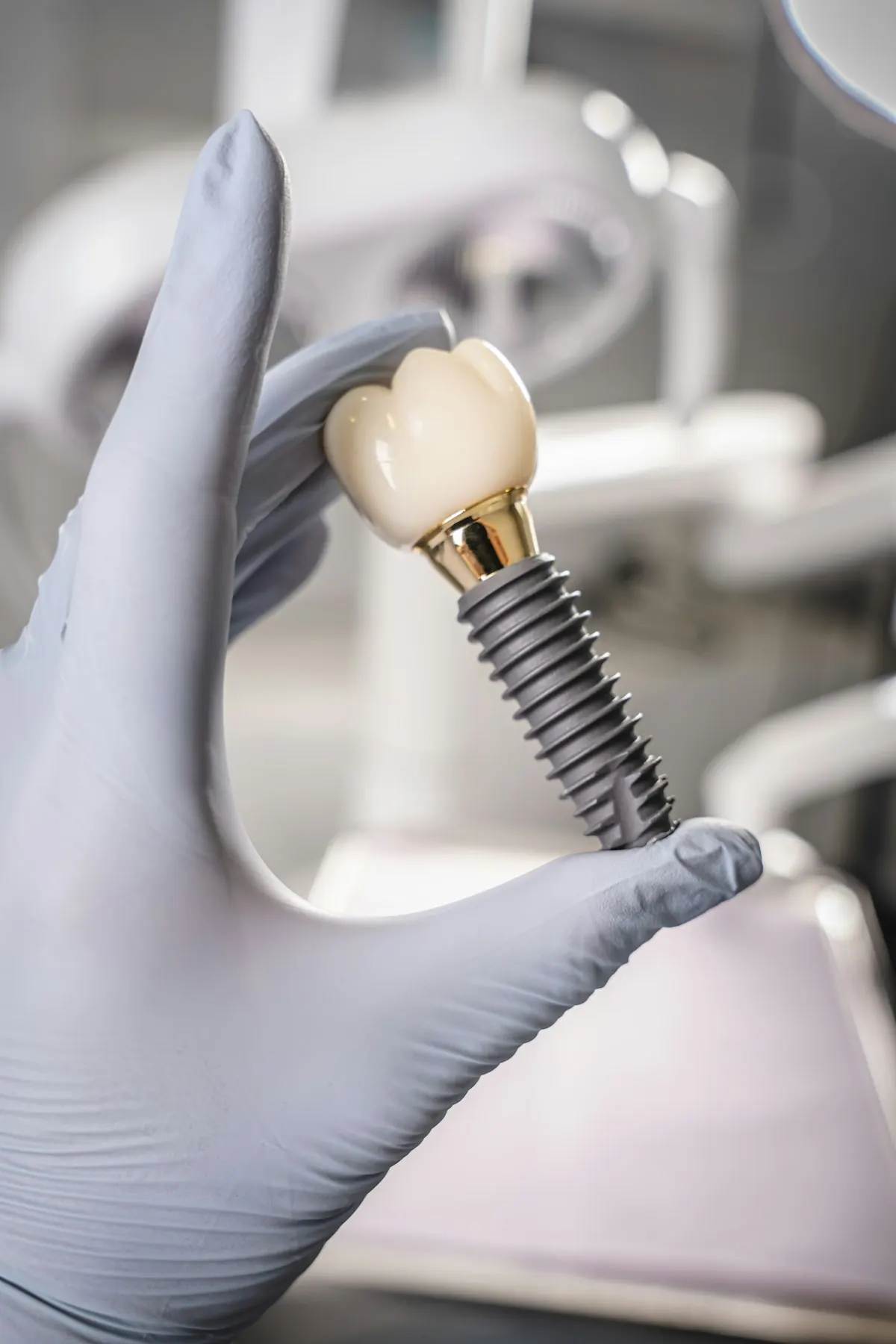 Eldivenli el, implant ve kron modelini tutuyor